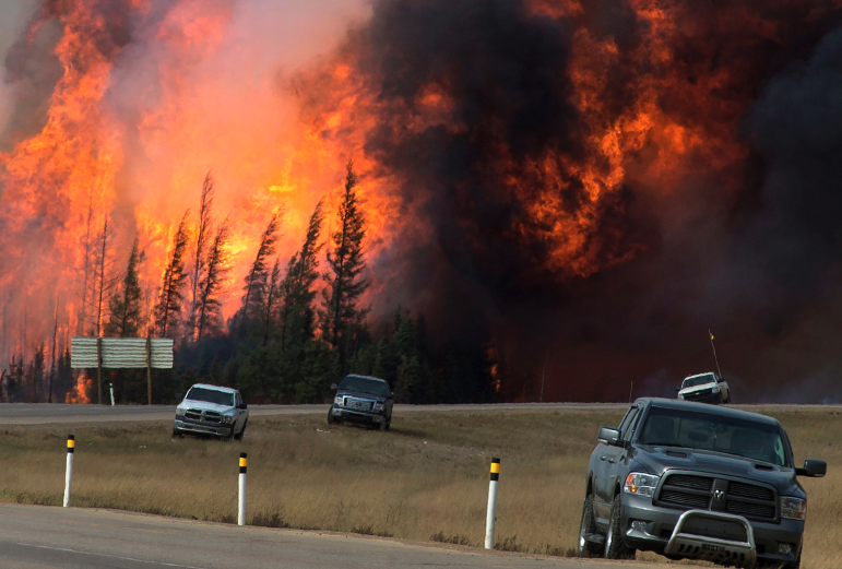 Trucks driving past a wildfire near Fort McMurray — where Converso's role in emergency communications was forged.
